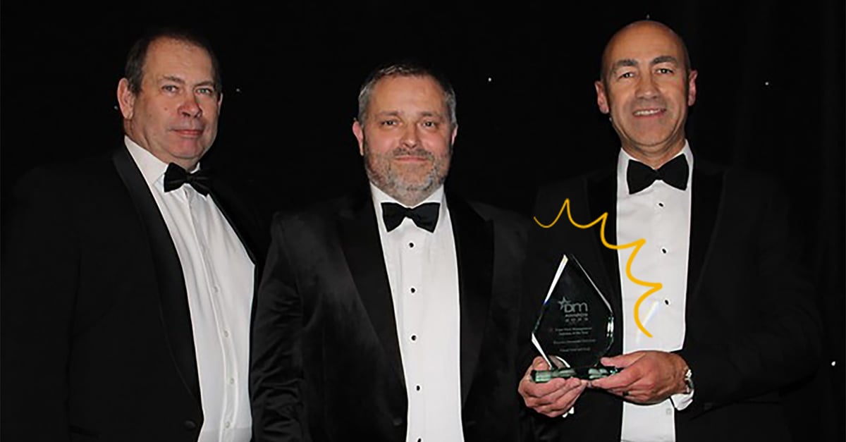 Three gentlemen holding the DM award